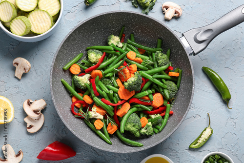 Vászonkép Frying pan with fresh vegetables on grey background