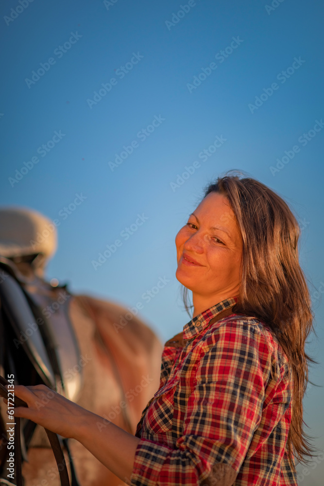 Portrait of a young beautiful girl with a horse on a ranch in a field.