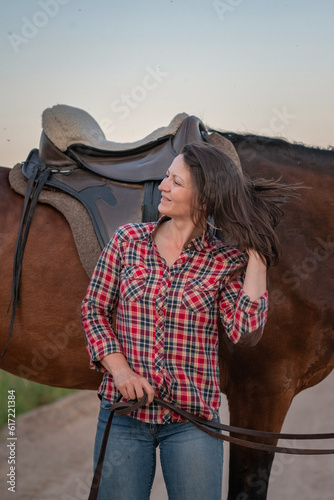 Portrait of a young beautiful girl with a horse on a ranch in a field.