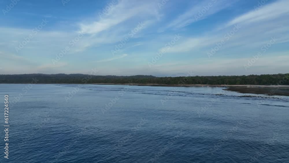 Rising drone clip over open ocean showing remote island tip of Java, Indonesia with calm waters