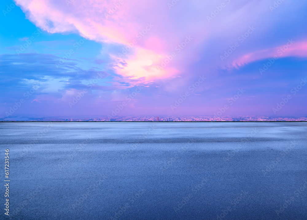 Obraz premium Asphalt road and city skyline with colorful sky clouds at sunset