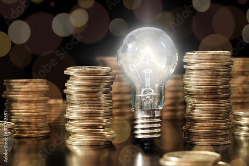 Financial literacy image. Knowledge of managing money. Lightbulb and stack of coins. photo