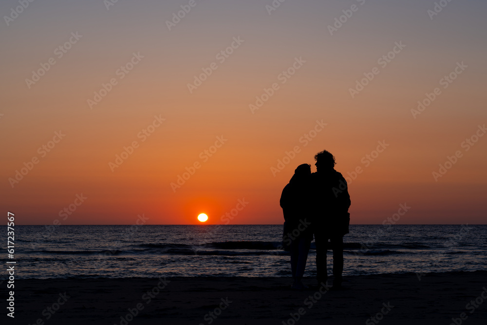 couple in love watching the sunset over the sea couple in love watching the sunset over the sea