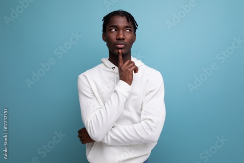 thinking model dark-skinned young brunette man looks away in a white sweater