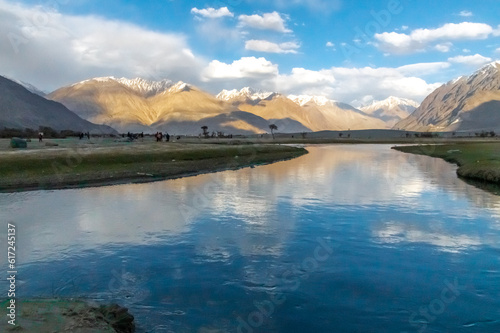 Hunder village in the Leh Nubra valley of Ladakh is famous for Sand dunes, Bactrian camels. Evening view of river and hills with dramatic clouds. © Srijita Photography