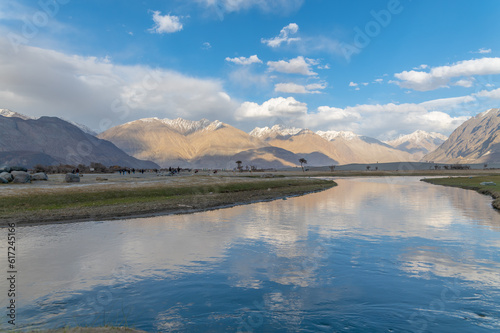 Hunder village in the Leh Nubra valley of Ladakh is famous for Sand dunes, Bactrian camels. Evening view of river and hills with dramatic clouds.