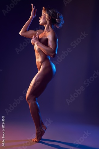 Sensual athletic female with naked body in dark studio