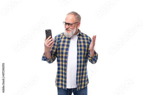 handsome elderly gray-haired retired man with a mustache and beard examines the gadget phone