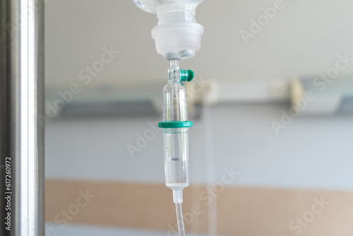 Infusion bag with drop counter on a IV stand pole or bottle hanger. Intravenous therapy, hanging bag of medicine for a patient receiving fluids through an intravenous line in a hospital room.