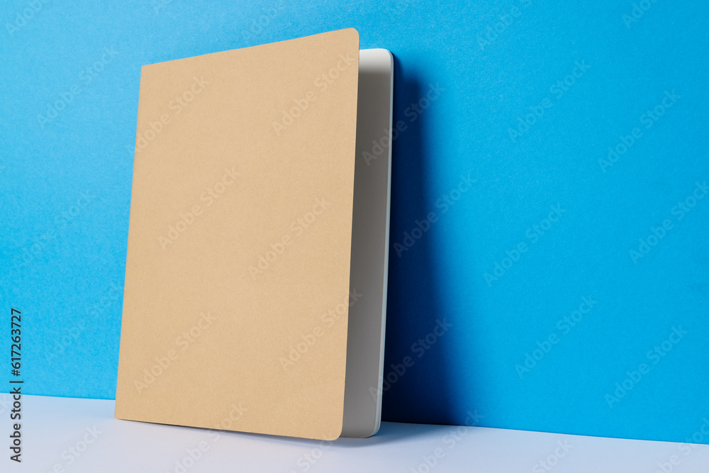Close up of beige notebook with copy space on blue background Close up of beige notebook with copy space on blue background