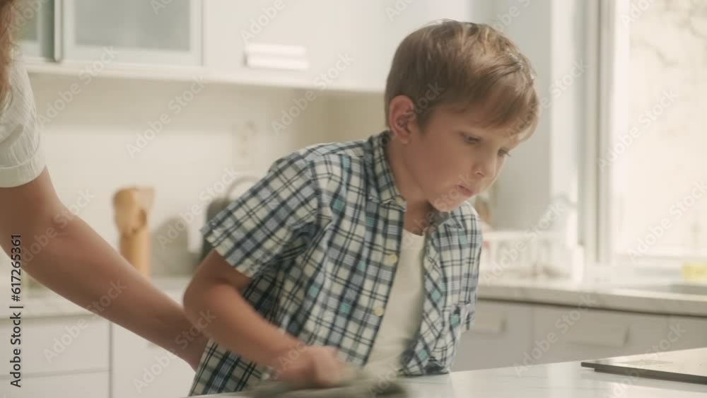 Mother and son doing housework together wiping table with detergent at kitchen Mother and son doing housework together wiping table with detergent at kitchen