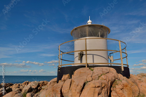 lighthouse on rocky coast face to baltic sea under blue sky in sweden