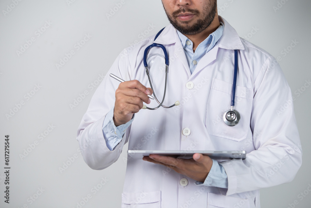 Portrait of male doctor using digital tablet while standing against grey background Portrait of male doctor using digital tablet while standing against grey background