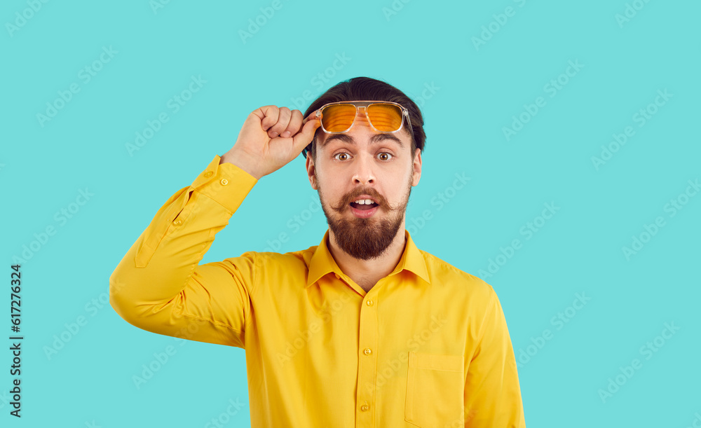 Stunned funny young bearded man isolated on blue studio background take off glasses shocked by deal or offer. Amazed male feel surprised with good seasonal promotion or discount. Stunned funny young bearded man isolated on blue studio background take off glasses shocked by deal or offer. Amazed male feel surprised with good seasonal promotion or discount.