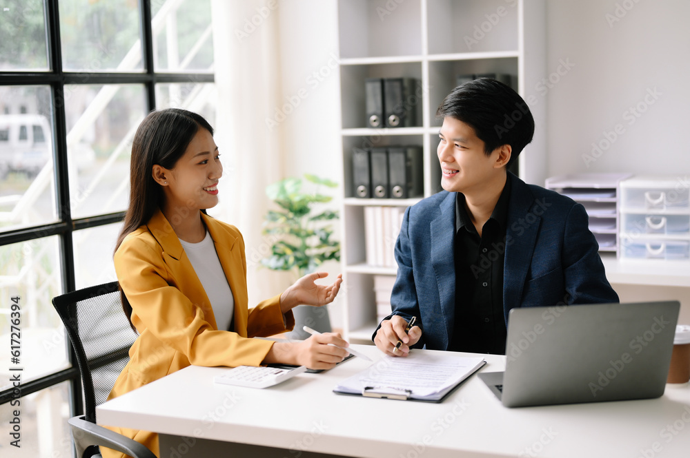 Two Asian business man and woman workers talking on the smartphone and using laptop Professionals in Teamwork Finance, Marketing, and Success Two Asian business man and woman workers talking on the smartphone and using laptop Professionals in Teamwork Finance, Marketing, and Success