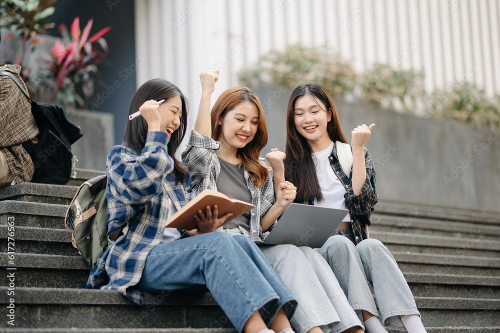 Three young Asian college students and a female student group work at the campus park Three young Asian college students and a female student group work at the campus park