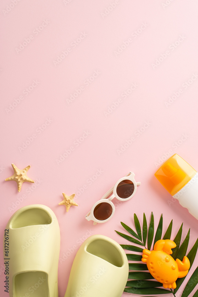 A bird's-eye vertical view of summer escape with kids, showcasing starfish, beach toys, slippers, sunglasses, sunscreen and palm leaf on pink isolated background, with empty space for text or advert