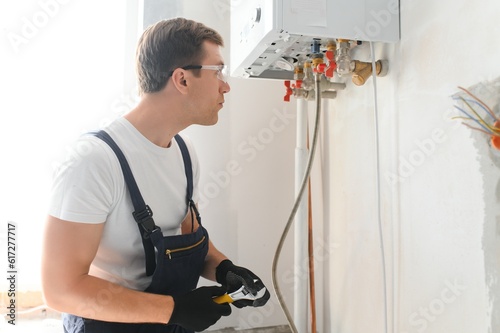 Gas engineer checking and cleaning a boiler during the inspection at home