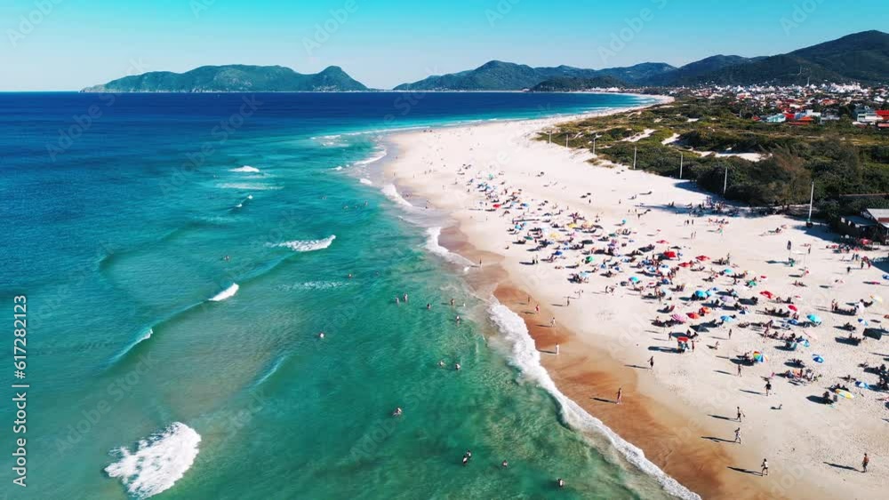 Aerial view of the sea with gentle waves and sandy beach with people relaxing on it. Campeche beach on Santa Catarina island in Brazil Aerial view of the sea with gentle waves and sandy beach with people relaxing on it. Campeche beach on Santa Catarina island in Brazil