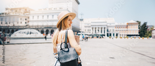 Young attractive smiling girl tourist exploring new city at summer