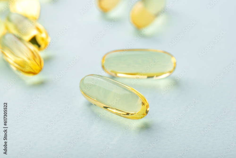 Omega 3 fish liver oil capsules on blue background. Close up, front view. Omega 3 fish liver oil capsules on blue background. Close up, front view.