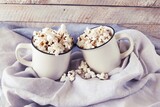 Two cups of delicious popcorn, on a linen cloth, on a wooden table