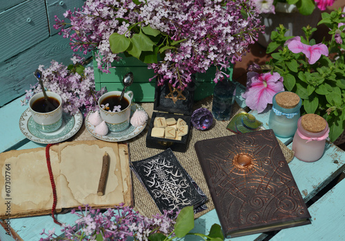 Vintage still life with open book or diary, tarot cards, cup and lilac flowers bouquet in the garden. Summer and spring season concept