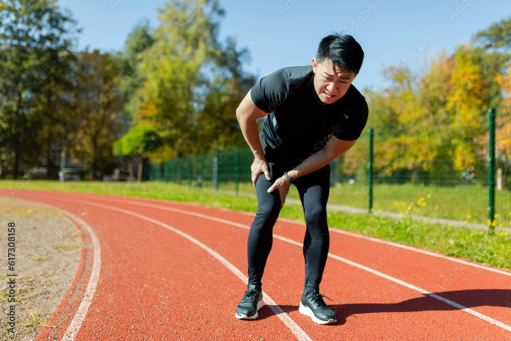 A runner injured his leg on a run in the afternoon, an Asian man has severe muscle spasm and pain in his leg during fitness and active exercise, a man in a tracksuit injured himself. A runner injured his leg on a run in the afternoon, an Asian man has severe muscle spasm and pain in his leg during fitness and active exercise, a man in a tracksuit injured himself.