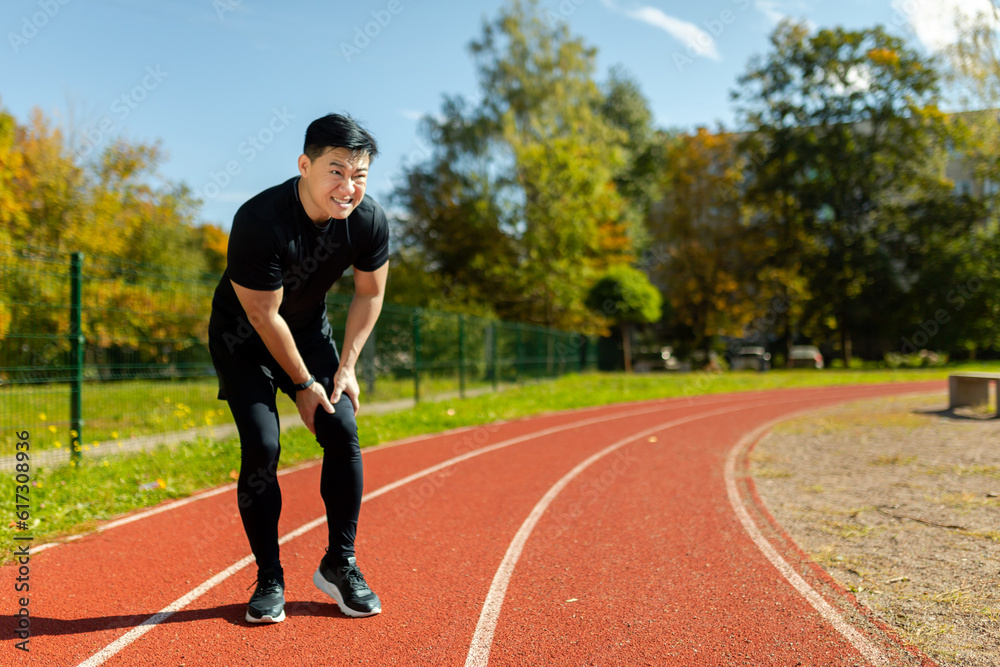 A runner injured his leg on a run in the afternoon, an Asian man has severe muscle spasm and pain in his leg during fitness and active exercise, a man in a tracksuit injured himself.