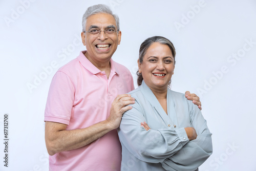 Portrait of loving senior Indian couple, standing on white background.