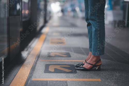 woman, Wearing Shoes, Standing at Yellow Arrow Road Sign "Left Side" on a floor at Train Station. Focus on Man Foot. Choice and Decision Making Concept.