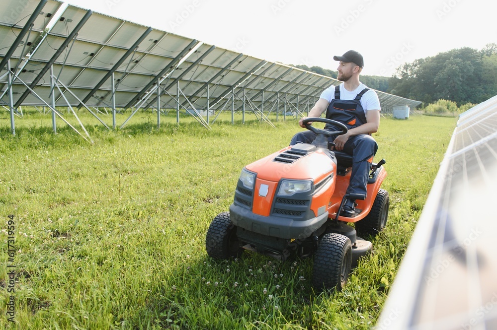A man mows the grass near the solar panels. Green energy