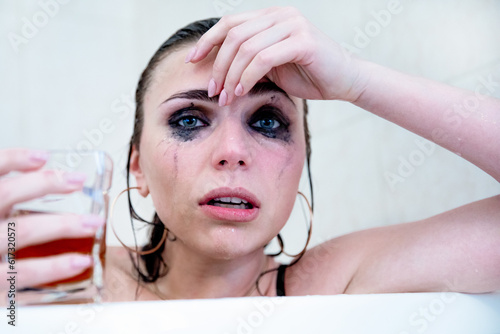 Young beautiful brunette with blue eyes, heavily flowing makeup and glass glass in her hand.