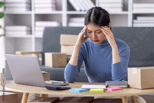 Young asian woman ecommerce SME business stressed leaning on package at home office, stressed headache Startup small business entrepreneur asian woman work package post shipping box delivery parcel © David
