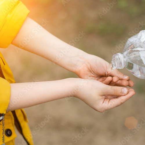 The child washes his hands from a bottle of water outside. Hygiene in nature, picnic.