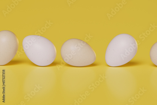 Eggs rolling on a yellow background. Sustainable and healthy eating habits