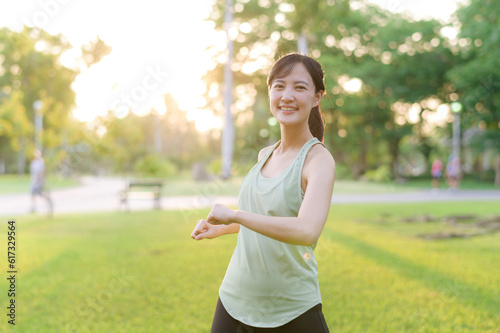 Female jogger. Fit young Asian woman with green sportswear stretching muscle in park before running and enjoying a healthy outdoor. Fitness runner girl in public park. Wellness being concept © Jirawatfoto