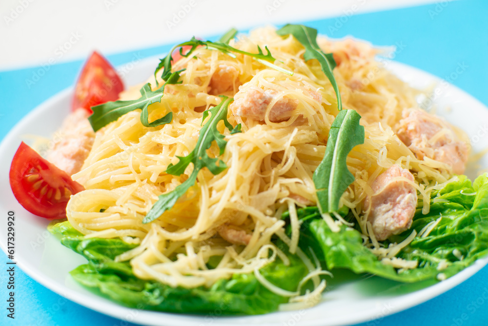 Spaghetti with salmon, cheese on a lettuce salad sprinkled with arugula and cherry tomatoes close-up. Spaghetti with salmon, cheese on a lettuce salad sprinkled with arugula and cherry tomatoes close-up.