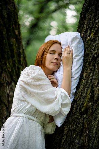 Woman sleeps soundly outdoors. She is lying on a pillow on a tree. Unity with nature, relaxation, recovery concept.