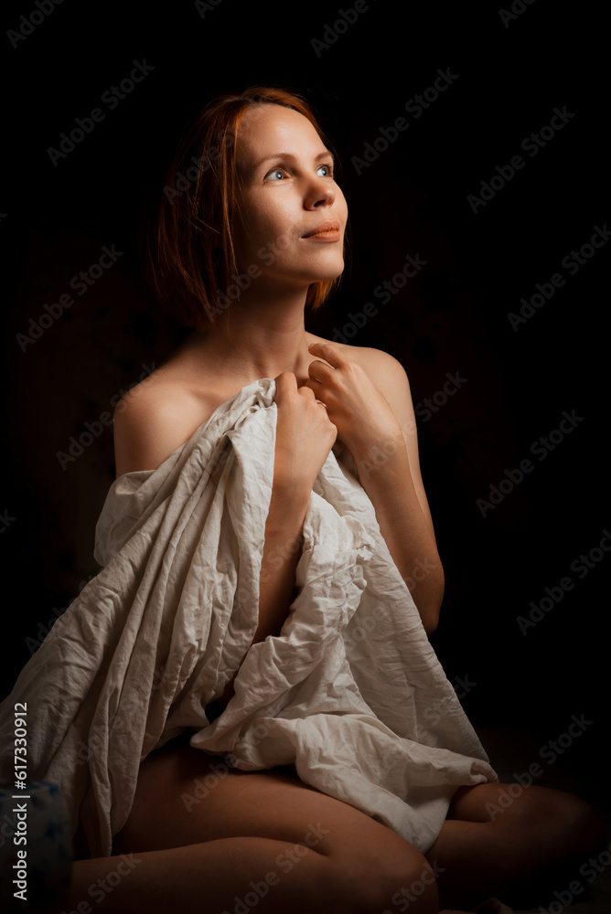 A cute woman wrapped in a white cloth is dreaming on a black background.
