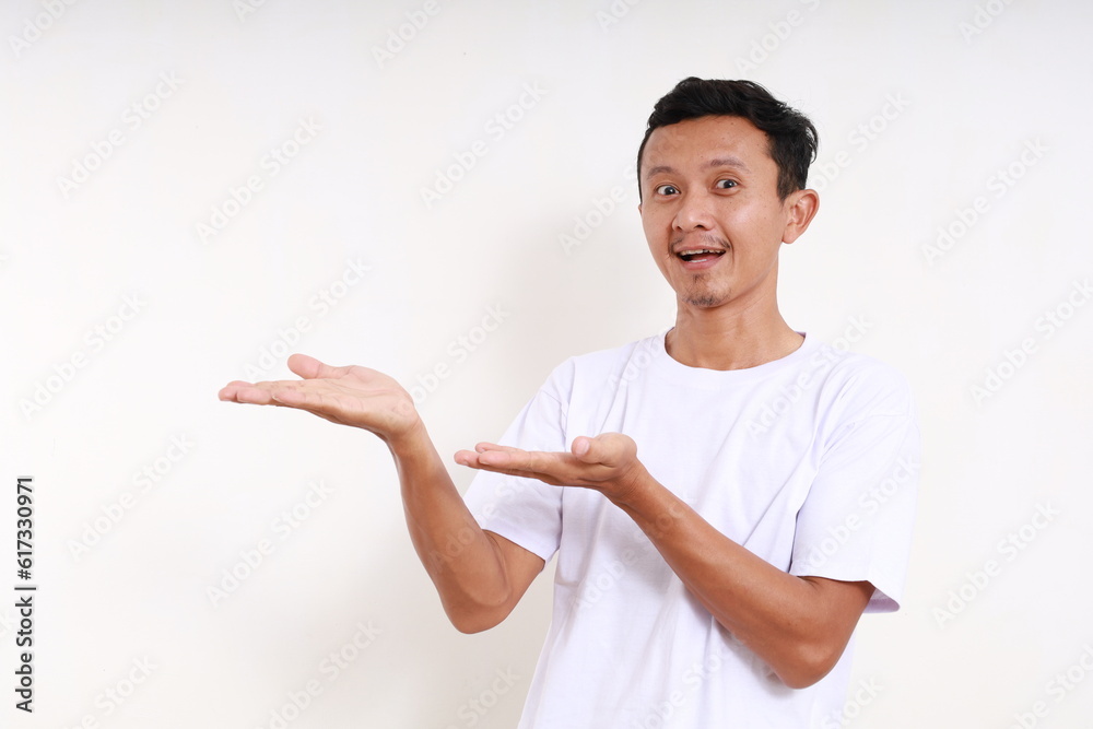Asian funny man standing while presenting something beside him. Isolated on white with copyspace Asian funny man standing while presenting something beside him. Isolated on white with copyspace