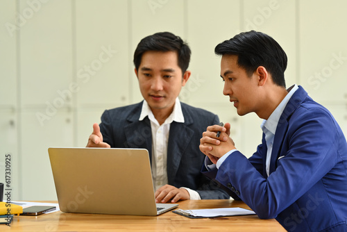 Shot of two startup businessman using laptop and discussing company financial project together