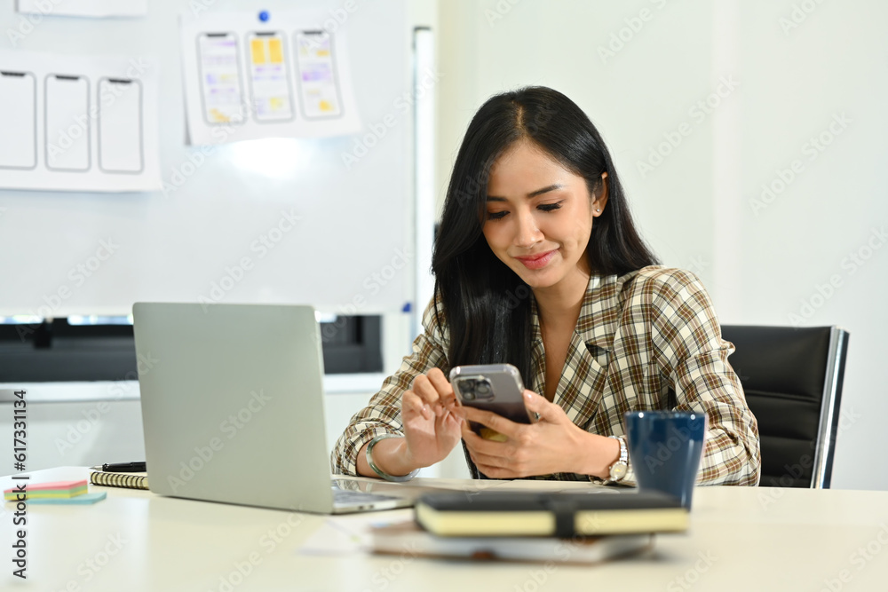 Pleasant young businesswoman typing massage or chatting online on smartphone at her workplace Pleasant young businesswoman typing massage or chatting online on smartphone at her workplace