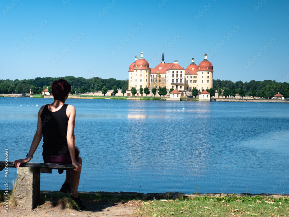 Woman hiker relax on the banch at lake surrounding Moritzburg Castle