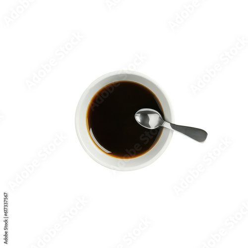 The image is an up-close shot of a cup of espresso coffee, placed on a table. The coffee cup features a spoon, which is resting inside the cup. 