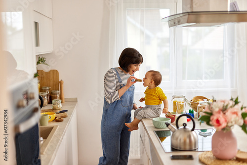 Mother feeding baby boy in the kitchen