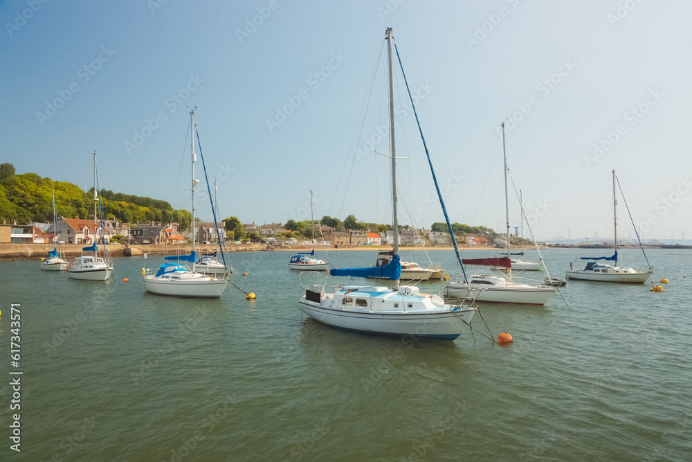 Sailboats anchored in the Firth of Forth on a sunny summer day at the coastal seaside village of Limekilns, Fife, Scotland, UK.