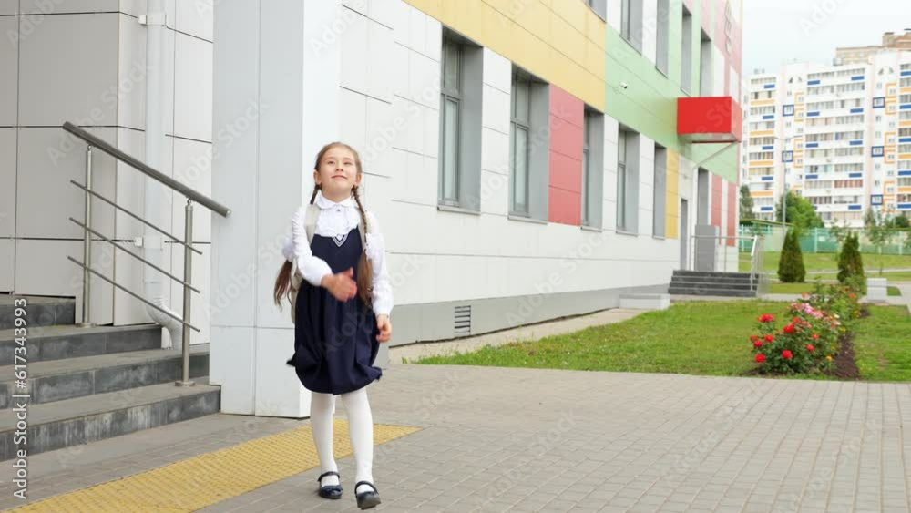 Junior schoolgirl leaves school with excited and happy expression skipping on stairs. Brown-haired girl in uniform walks jumping on way home Junior schoolgirl leaves school with excited and happy expression skipping on stairs. Brown-haired girl in uniform walks jumping on way home