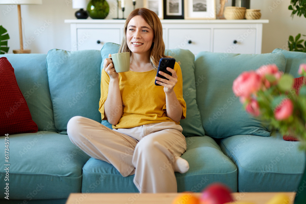 Woman using smartphone while drinking coffee at her home in the morning Woman using smartphone while drinking coffee at her home in the morning