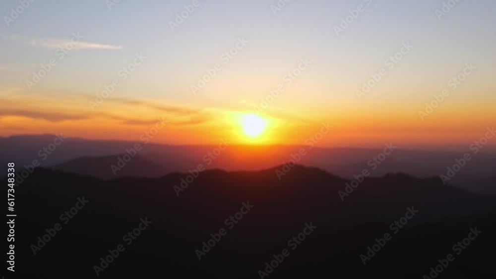 Rack focus of setting sun casting orange red golden hour light and mountains to a blur Rack focus of setting sun casting orange red golden hour light and mountains to a blur